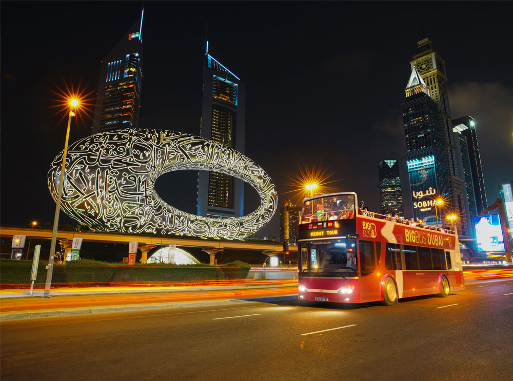 Big Bus Tour passing Museum of the Future at night