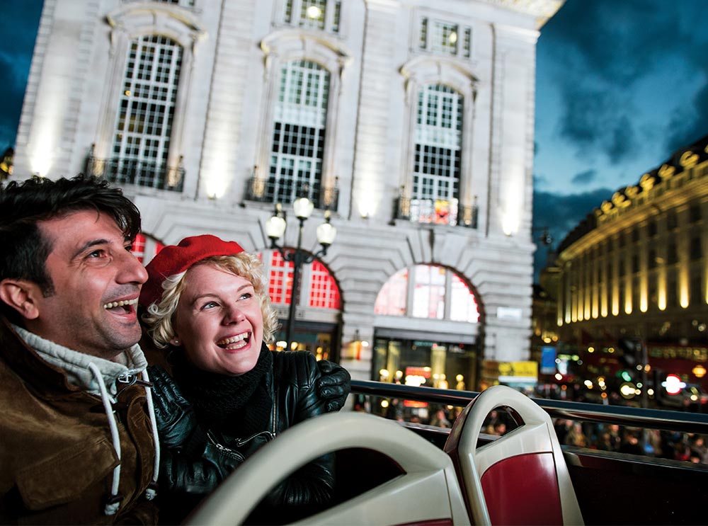 Un homme et une femme admirent un monument de Londres lors d'une visite nocturne en Big Bus