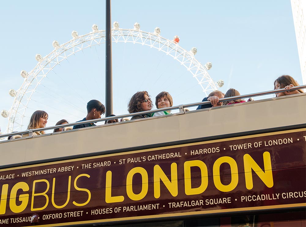 Des gens sur le pont supérieur du Big Bus Tour avec le London Eye en arrière-plan