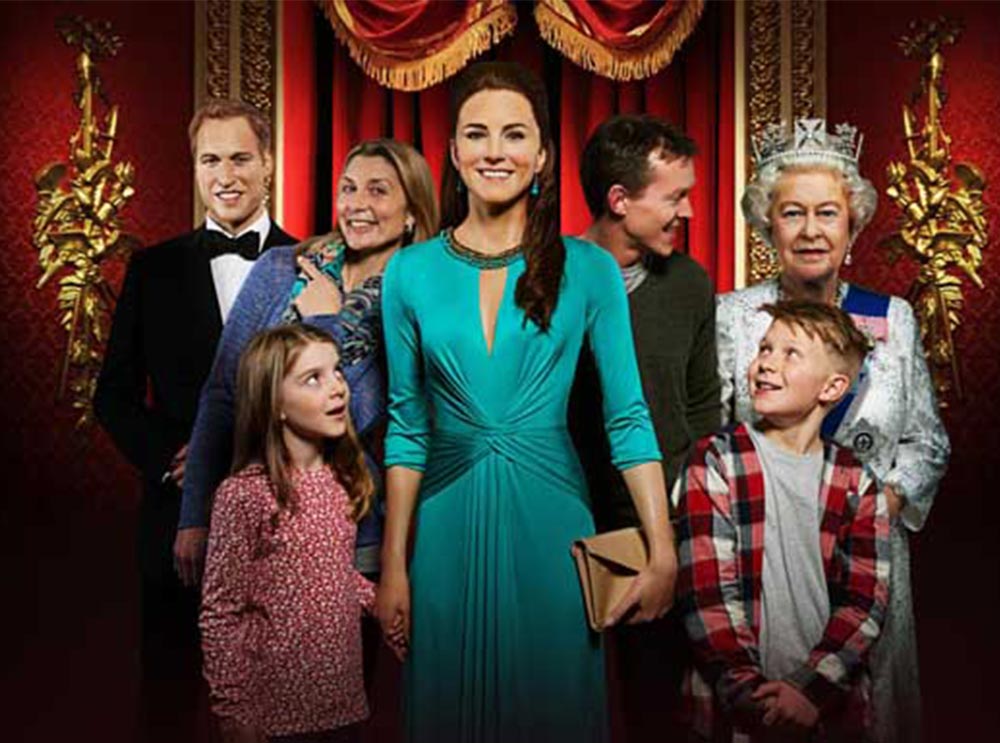 A family standing with wax figures of the British Royal Family in Madame Tussauds