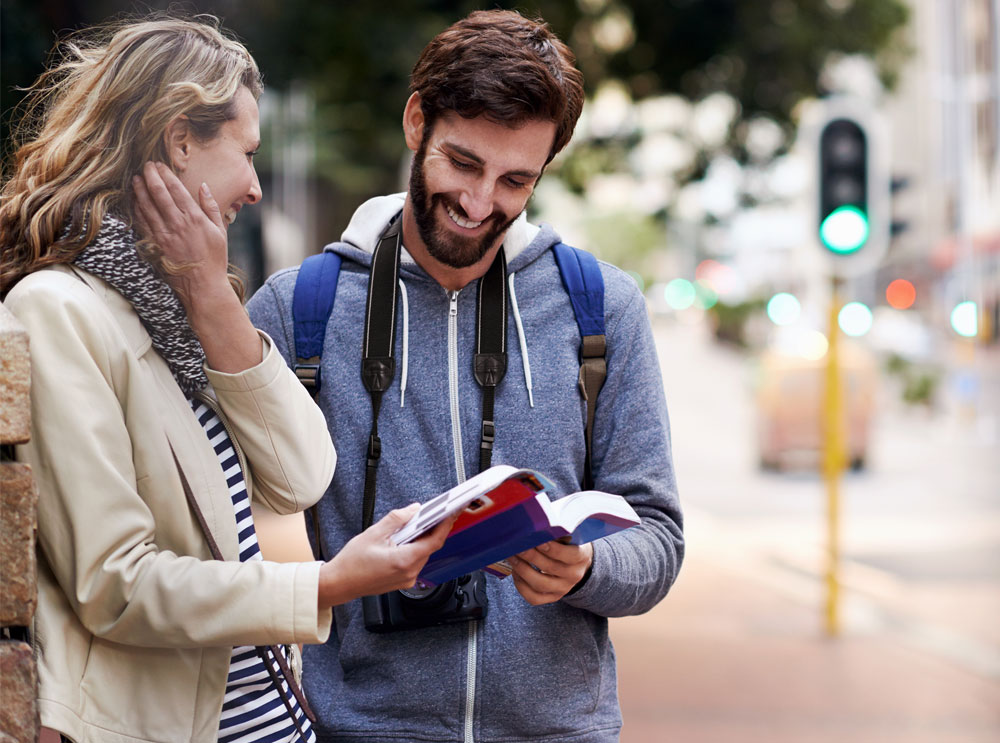 Couple reading book on sidewalk