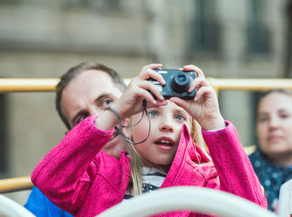 Girl sitting with her dad taking a photo on a camera