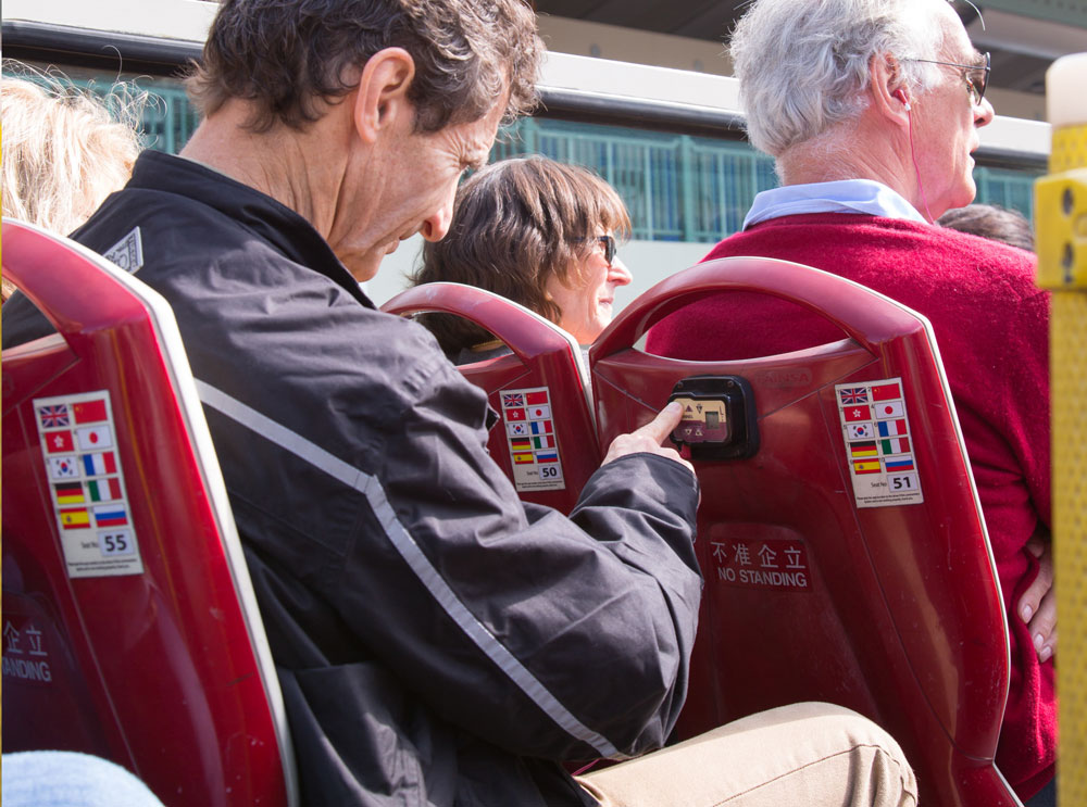 Man adjusting audioguide options on bus tour