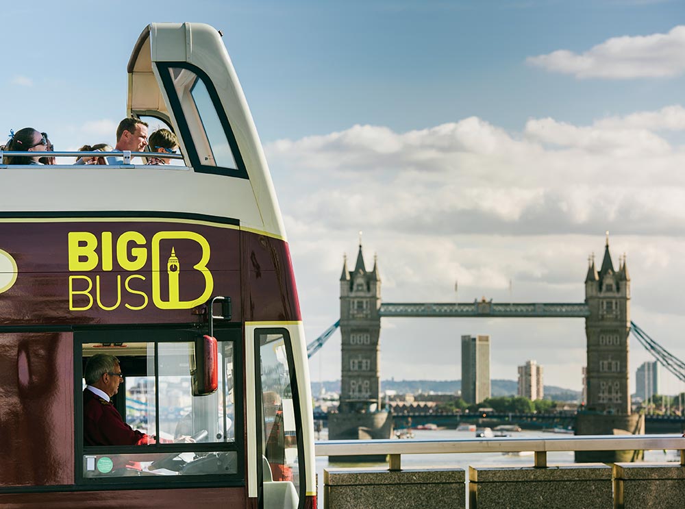 Big Bus Tours in London, with tower bridge in distance