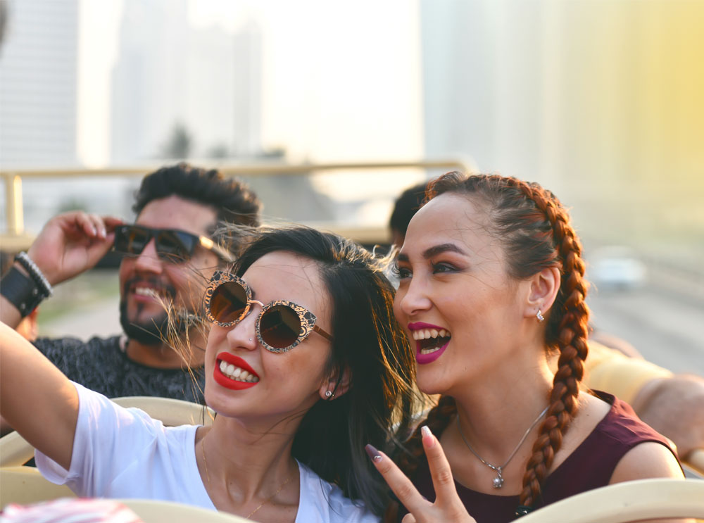 Freunde posieren für ein Selfie auf dem Oberdeck eines Sightseeing-Tourbusses
