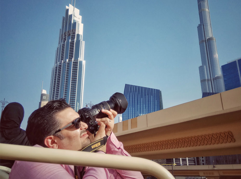 Man taking a photo from the top deck of a bus tour
