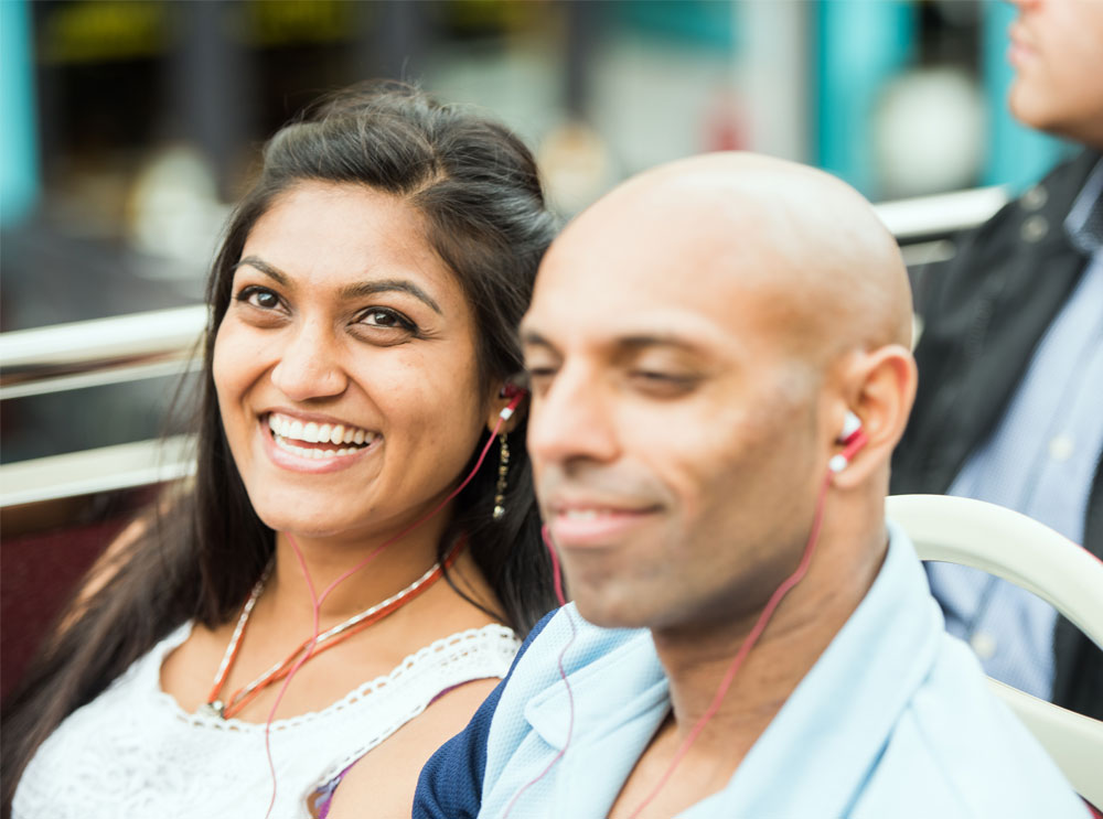 Couple listening to the audio guide on a bus tour
