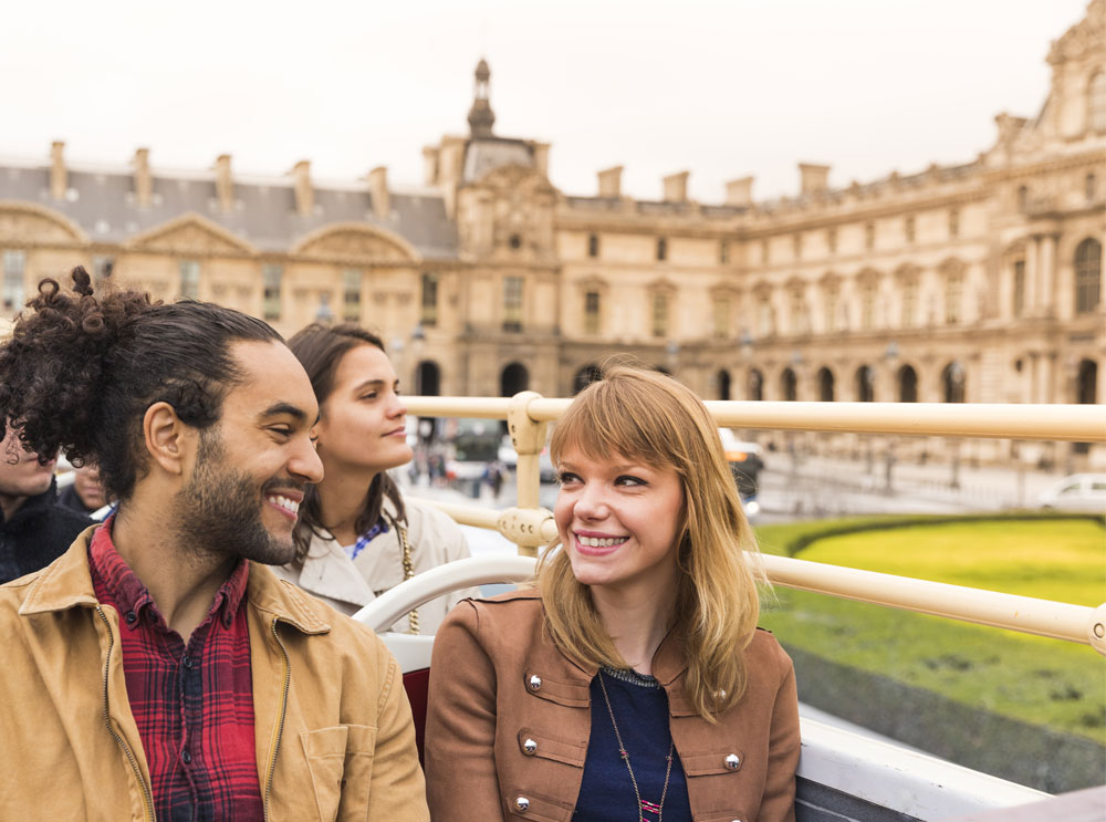 Couple on a hop on, hop off bus tour in Paris
