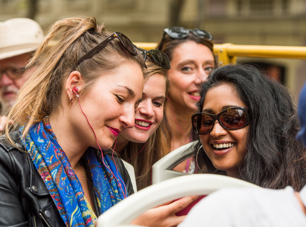 Friends listening to audio commentary on a sightseeing bus tour
