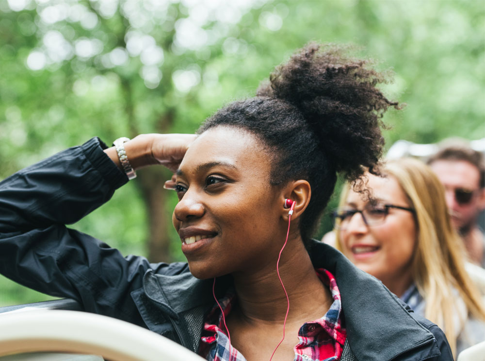 Girl listening to audio guide on top deck of  bus