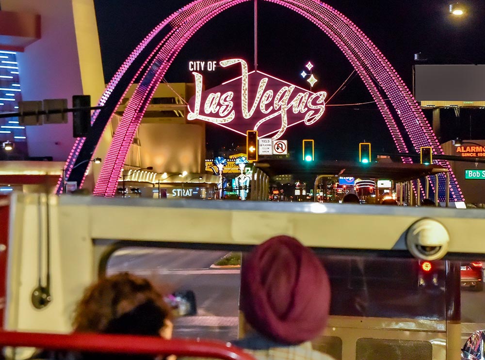 Big Bus nähert sich nachts dem Schild "City of Las Vegas"