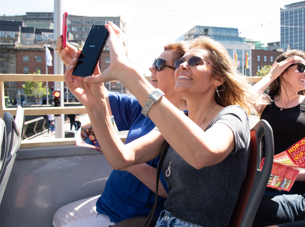 Friends taking photos on a sightseeing bus tour