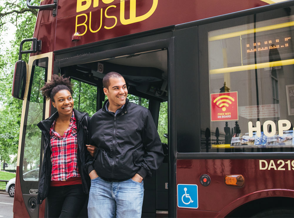 Couple hopping off a Big Bus Tour bus
