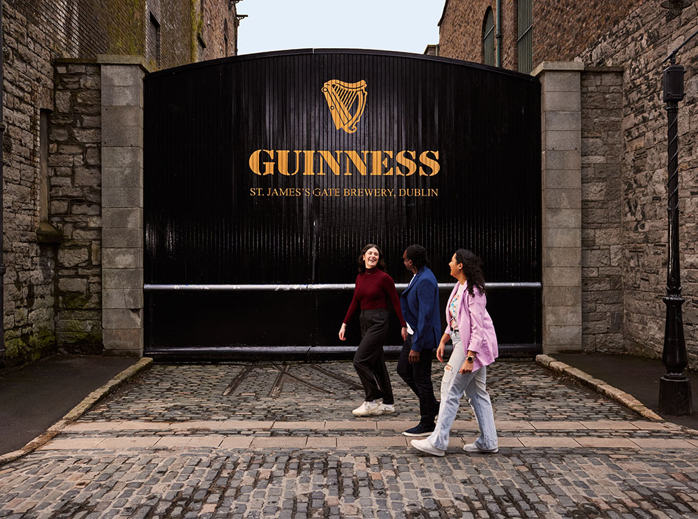 Guinness storehouse in Dublin, with people walking by it 