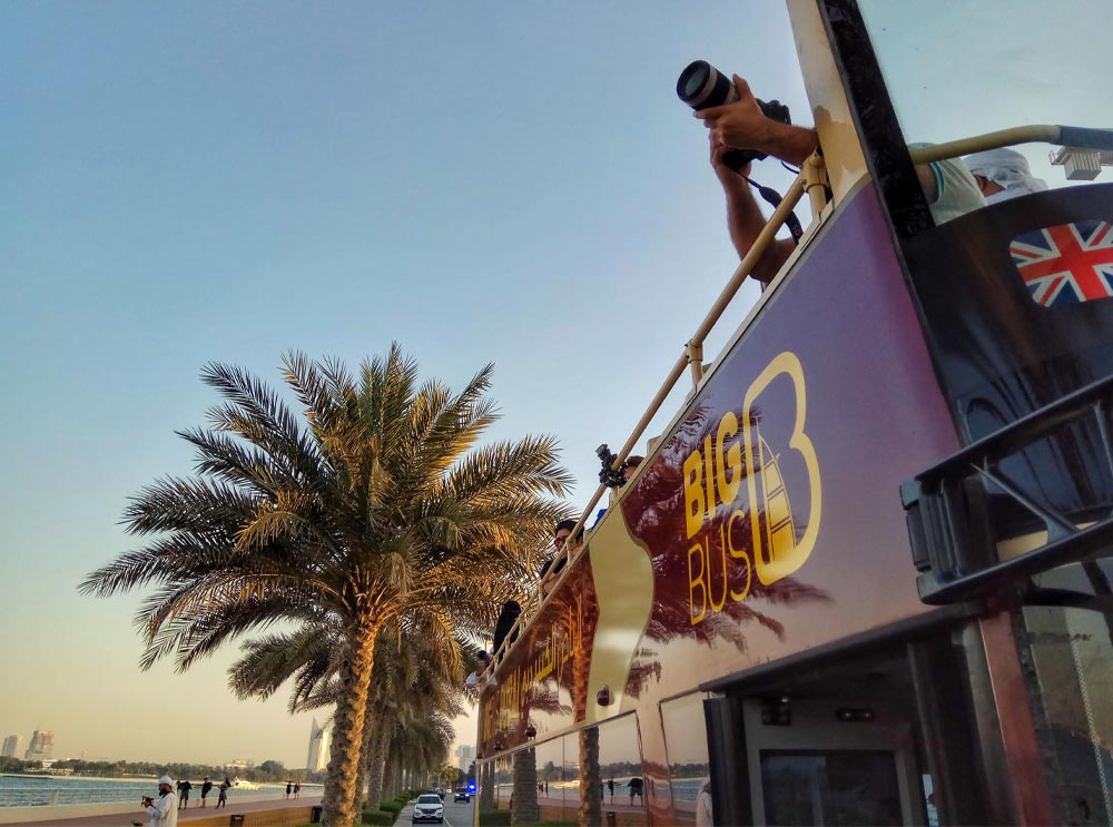 A man takes a photograph from the top deck of a Big Bus Tours Dubai tour