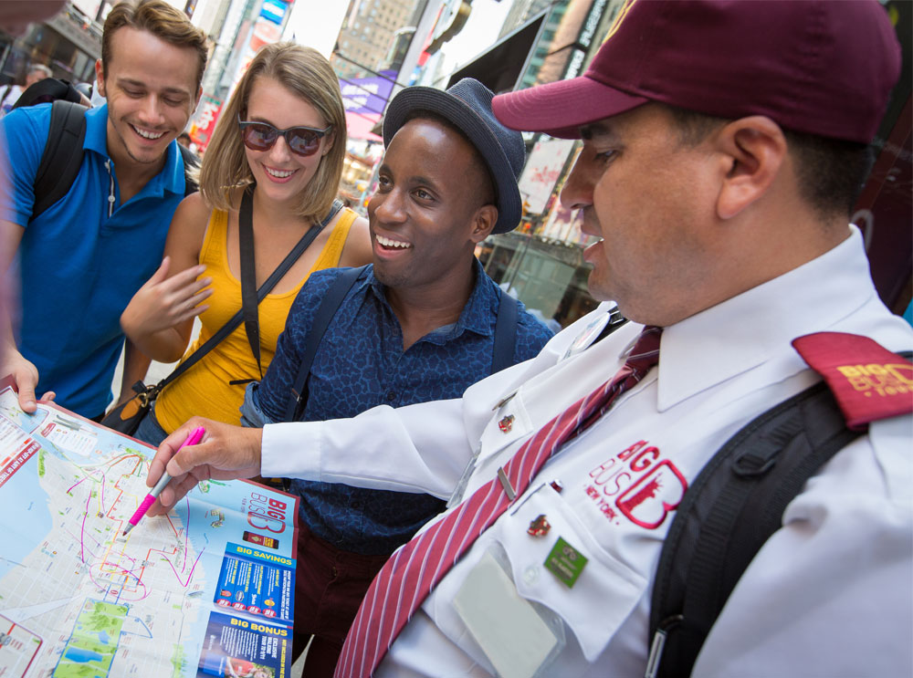 Mitarbeiter von Big Bus Tours zeigt einer Gruppe von Freunden die Karte
