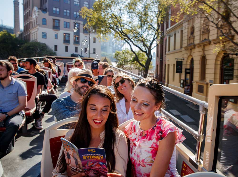 Women look at Big Bus Tours Sydney brochure on board the bus