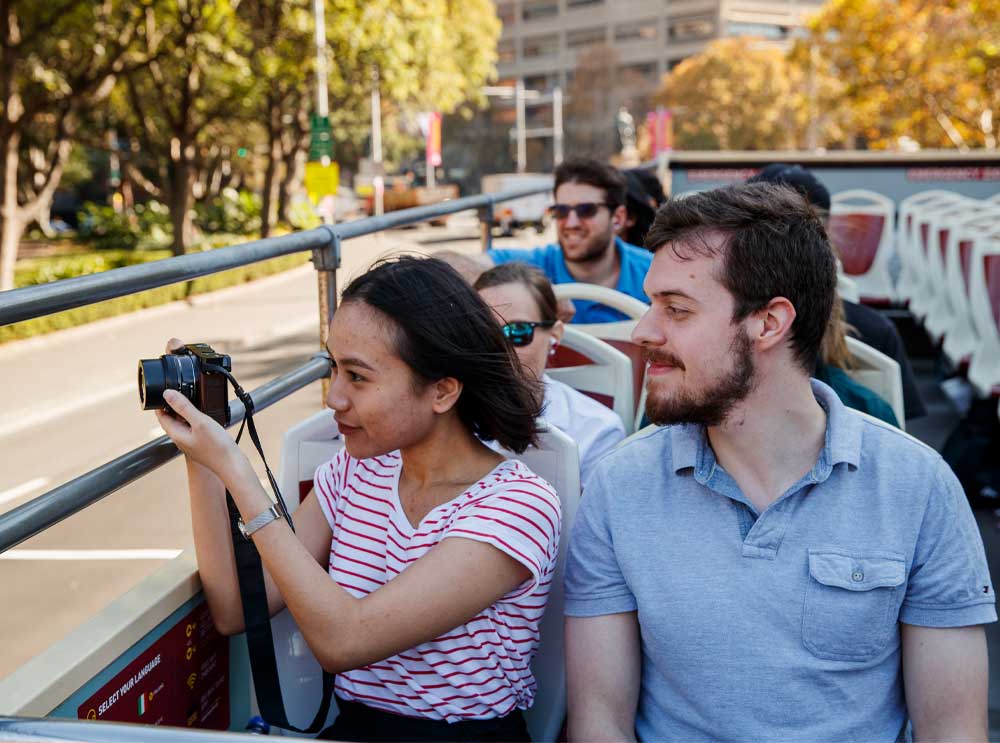 Woman takes photos from top deck of Big Bus Tour in Sydney