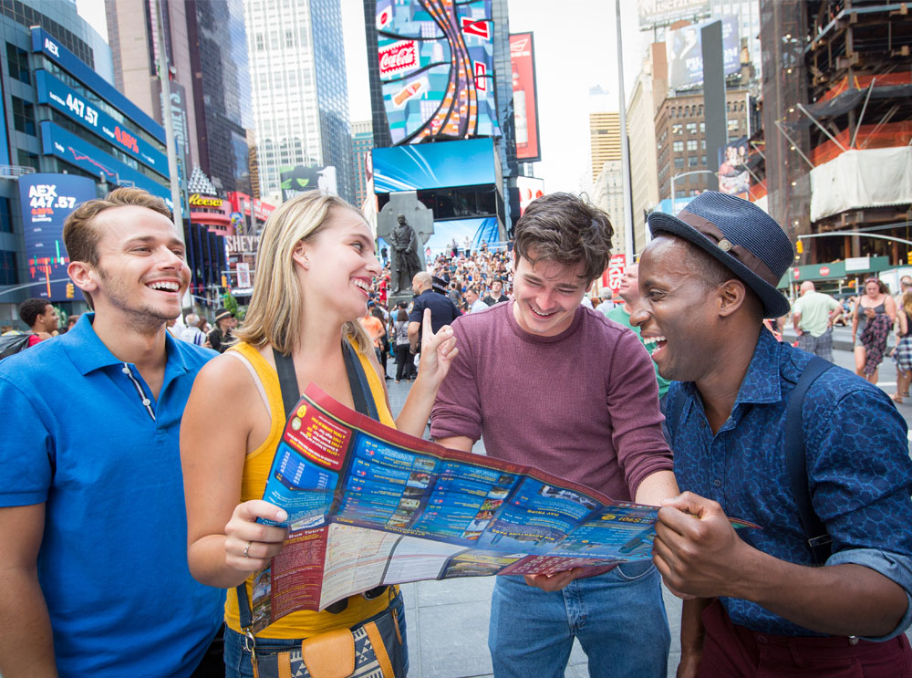 Freunde schauen sich am Times Square in New York einen Prospekt von Big Bus Tours an