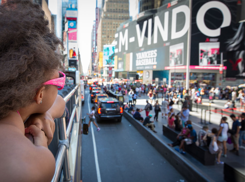 Ragazza sul bus turistico a New York che guarda Times Square
