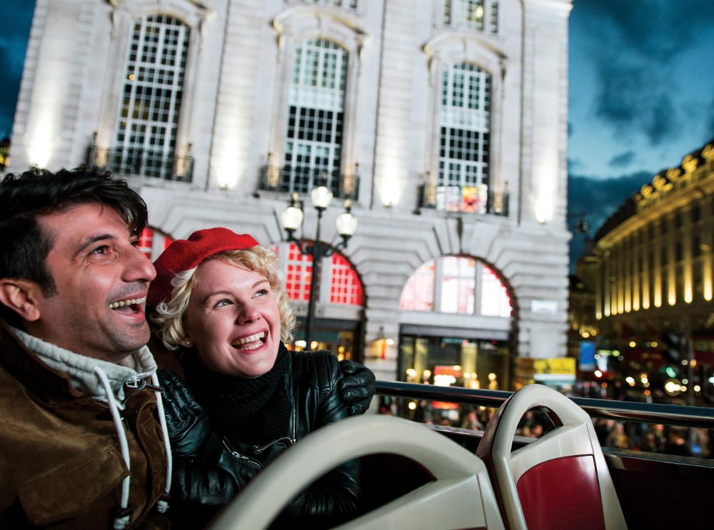 Paar fährt auf Big Bus Night Tour durch Piccadilly Circus