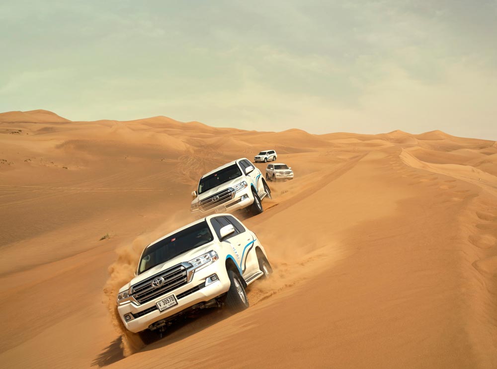 4 Tour Dubai Toyota Landcruisers travel through the desert