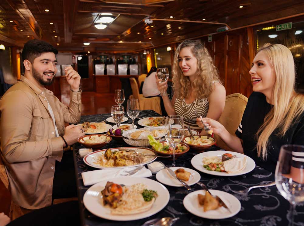 Friends enjoy dinner on Dubai Creek Dhow Cruise