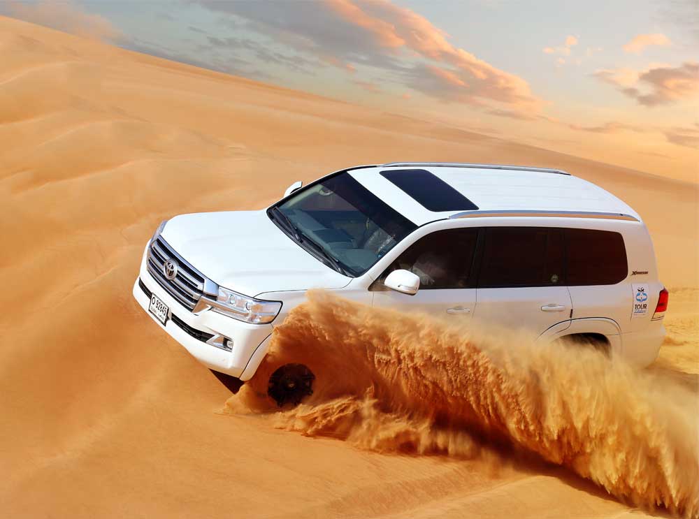 A white Toyota Landcruiser blazes through the desert sand