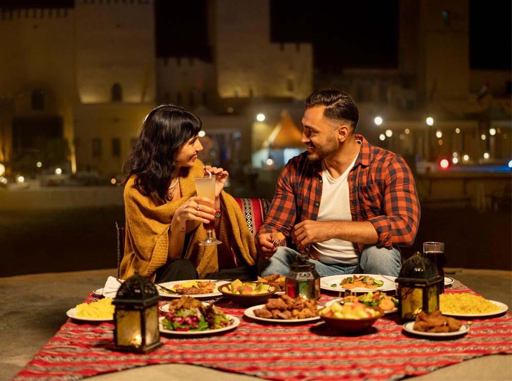 A couple share a meal at the Sahara Desert Fortress