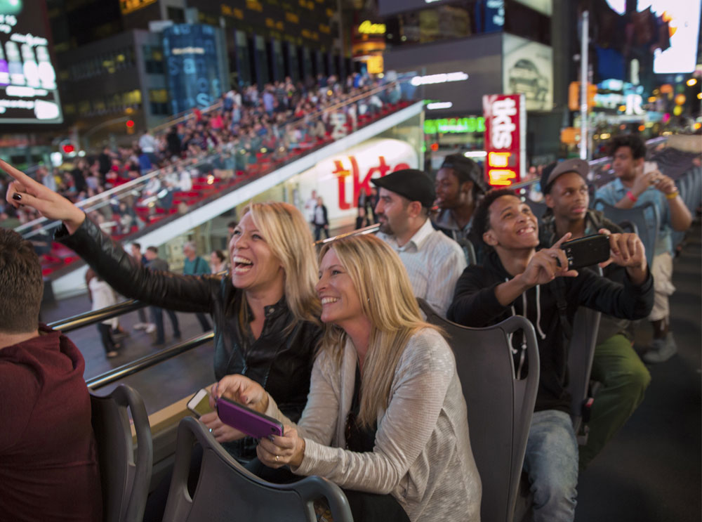 Friends pointing and taking photos on a sightseeing bus tour
