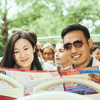 Couple looking at big bus travel brochure while on board the bus