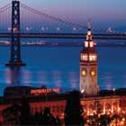 Vista nocturna del edificio de la Terminal de Ferries de Embarcadero y el Puente de la Bahía de Oakland, en San Francisco