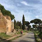 Cyclist passes ancient ruins on Appian Way