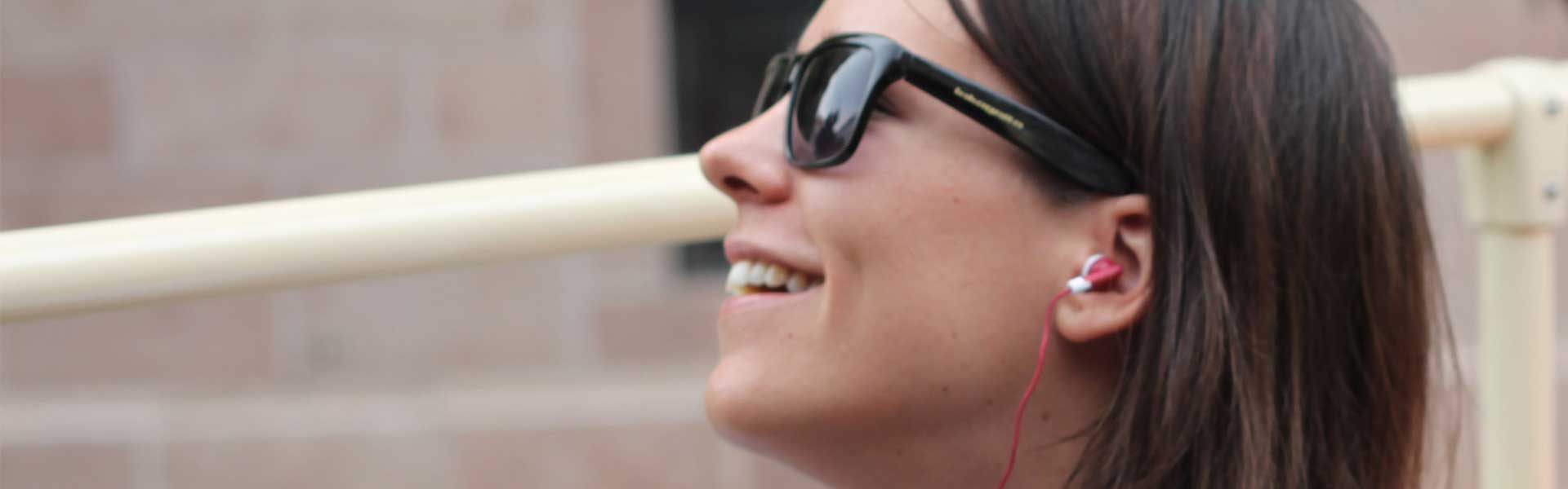 Donna con occhiali da sole che ascolta un'audioguida pre registrata su un Big Bus Tour tramite cuffie rosse